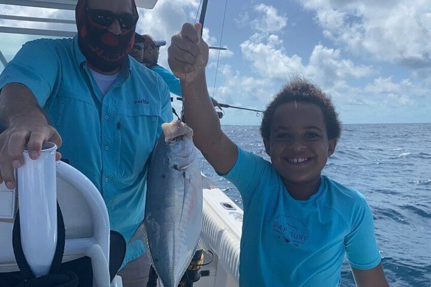 A person holding a fish on a boat with the ocean in the background. 5