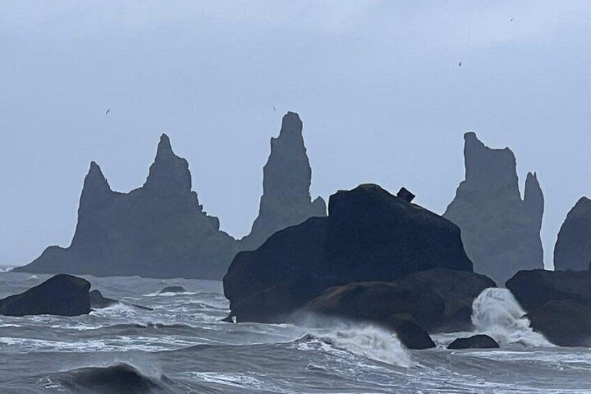 A coastal scene with large rock formations and rough sea waves. 3