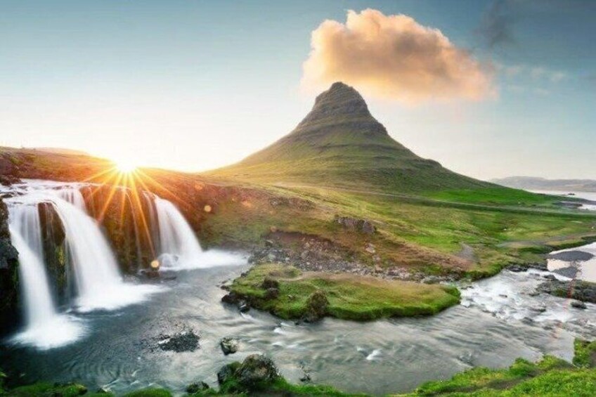 A waterfall, a grassy landscape, and a mountain. 1