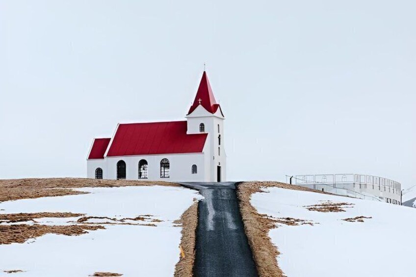 A white church with a red roof and a steep driveway. 3