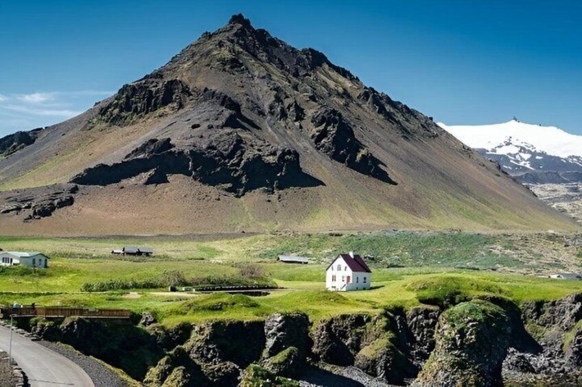 A white house on a grassy hill with a mountain in the background. 4