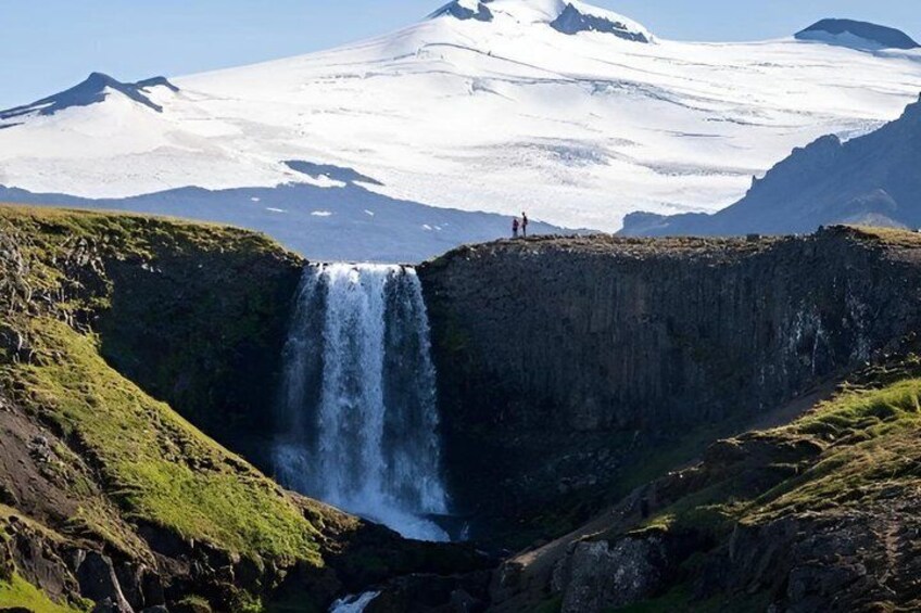 A waterfall cascading down a rocky cliff with a glacier in the background. 5