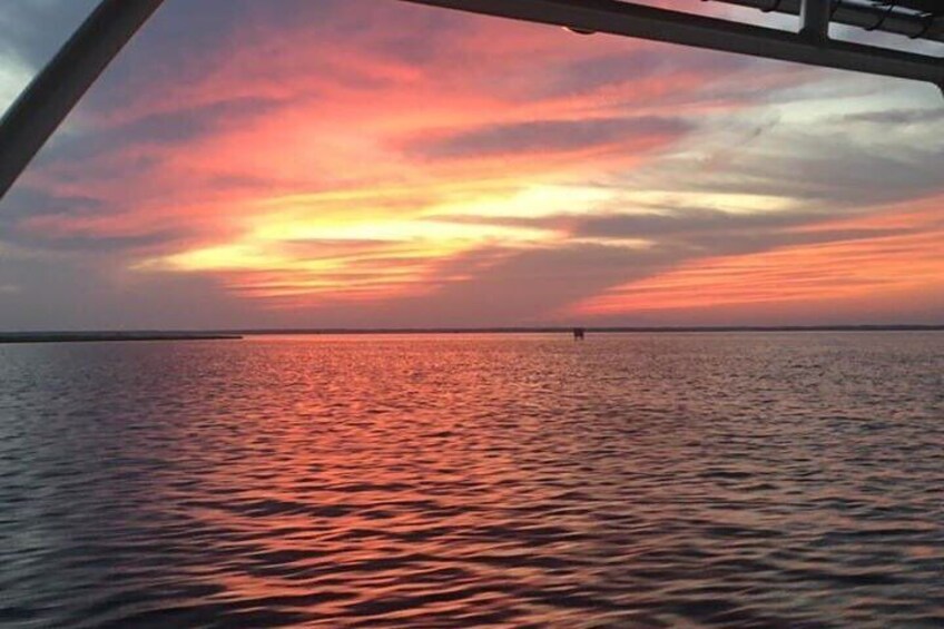 A sunset over a calm sea with a boat in the foreground. 2