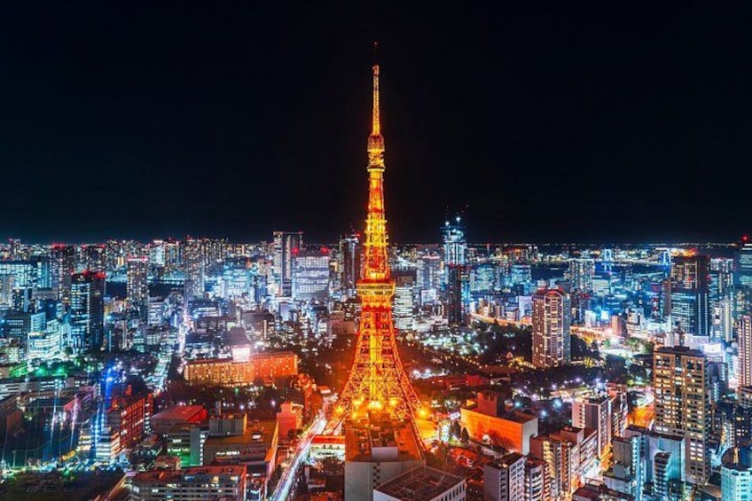 A cityscape at night with a prominent illuminated tower in the center, surrounded by densely packed buildings. 5