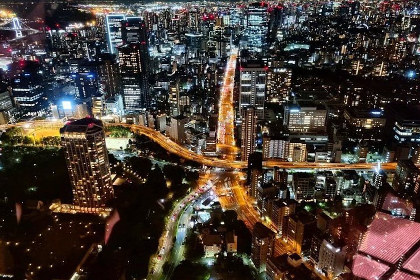 A nighttime cityscape with illuminated buildings, a prominent highway, and a dense urban layout. 2