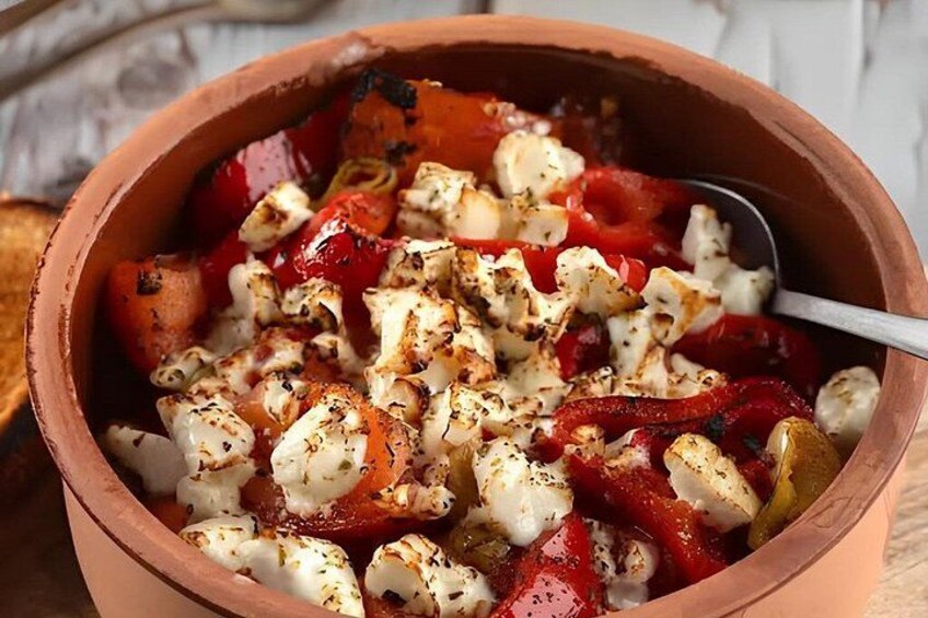 A terracotta bowl filled with roasted vegetables and feta cheese. 4