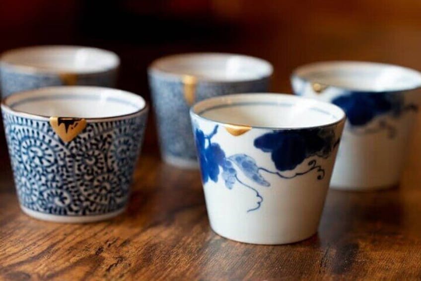 A collection of ceramic cups with blue and white patterns on a wooden surface. 5