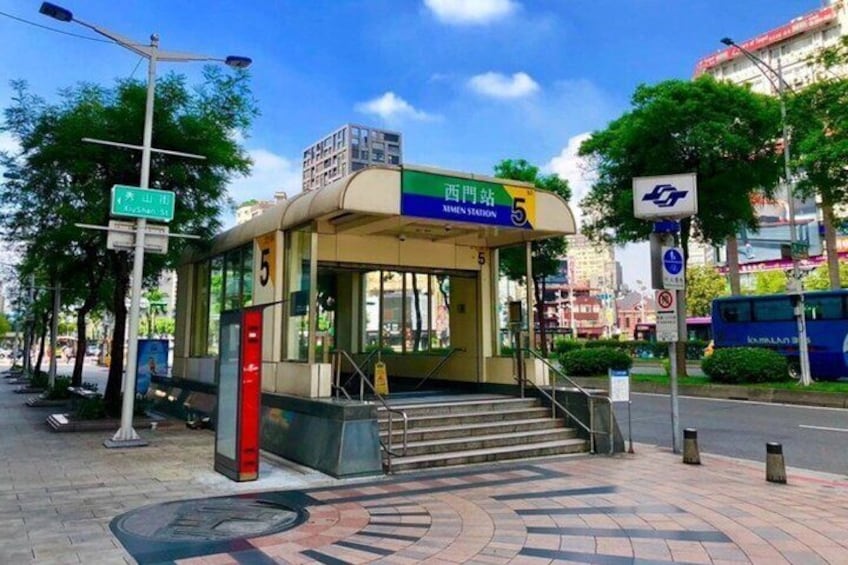 A bus stop with a shelter, stairs leading up to it, and a bus in the background. 2