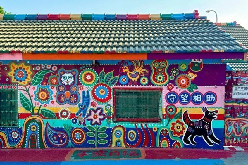 A colorful building with a tiled roof and vibrant murals. 1