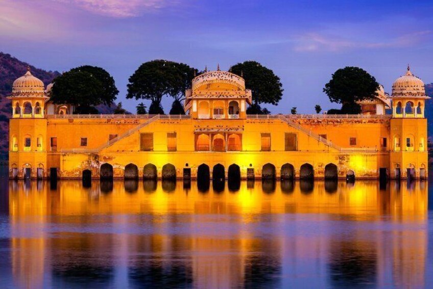 A historic building with domed structures and arched walkways, reflecting in a calm body of water. 4