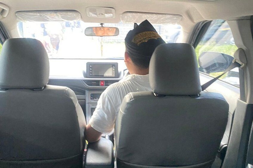 The interior of a car with two seats, a dashboard, and a rearview mirror. 3