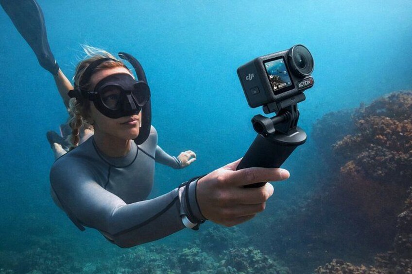 A person scuba diving underwater, holding a camera on a tripod. 2