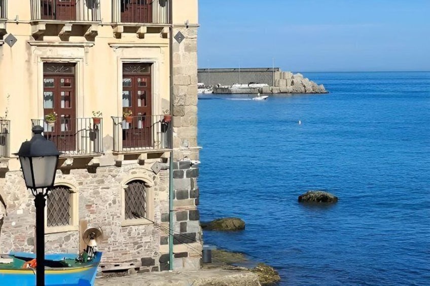 A coastal building with a stone facade, a blue boat, and a rocky breakwater in the background. 4