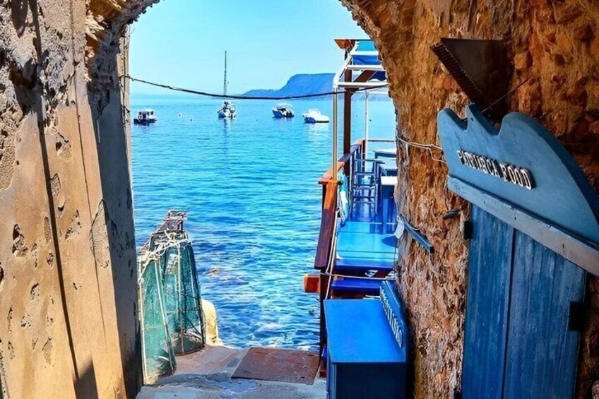 A coastal scene with boats docked at a pier, a clear sky, and a rocky shoreline. 2