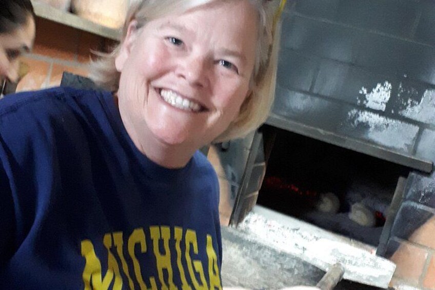 A person wearing a blue shirt with 'Michigan' written on it, standing in front of a fireplace. 2