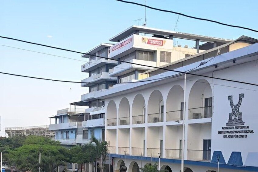 A multi-story building with a white facade and blue accents, featuring a prominent logo on the side. 5