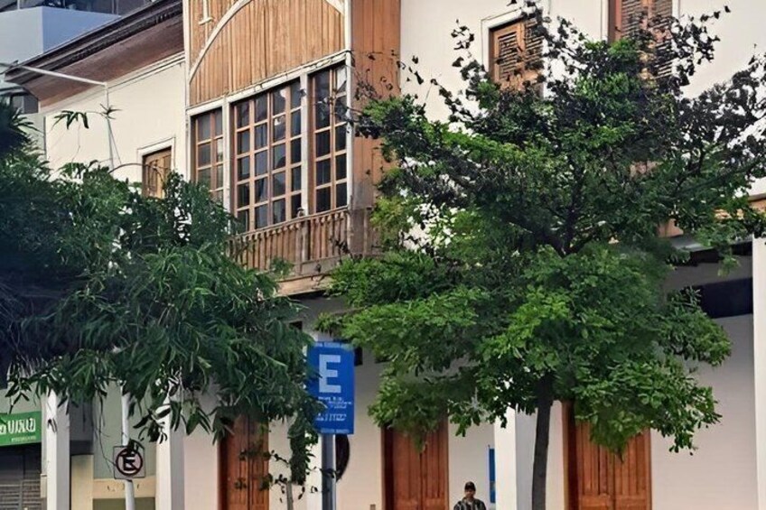 A building with a balcony, a tree, and a blue parking sign. 4
