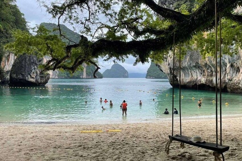 A beach with clear water, people swimming, and a swing set. 3