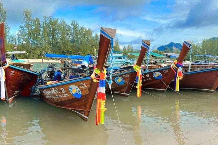 A row of traditional boats docked at a pier with a mountainous backdrop. 2