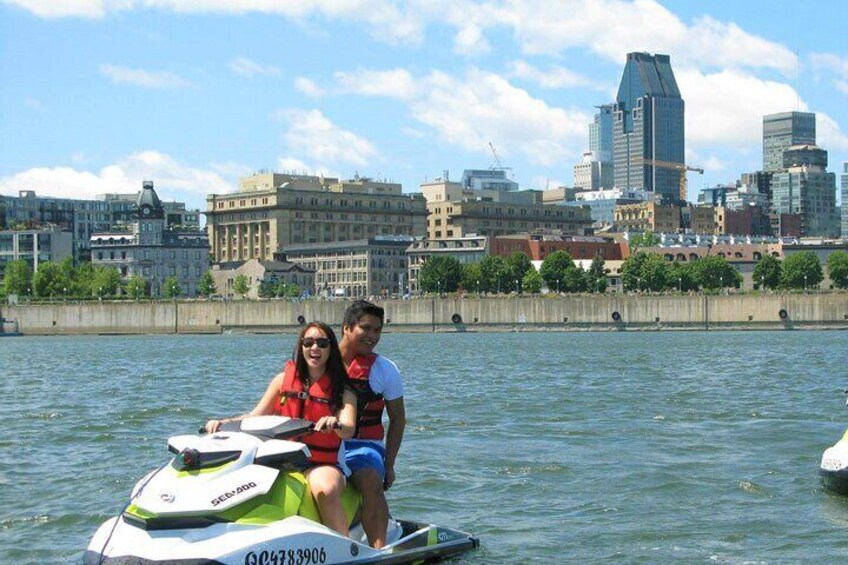 Two people on a jet ski with a city skyline in the background. 2