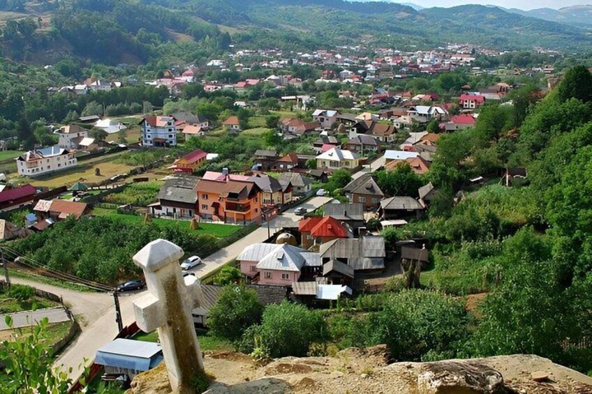 A village with houses, a statue, and a hilly landscape. 3
