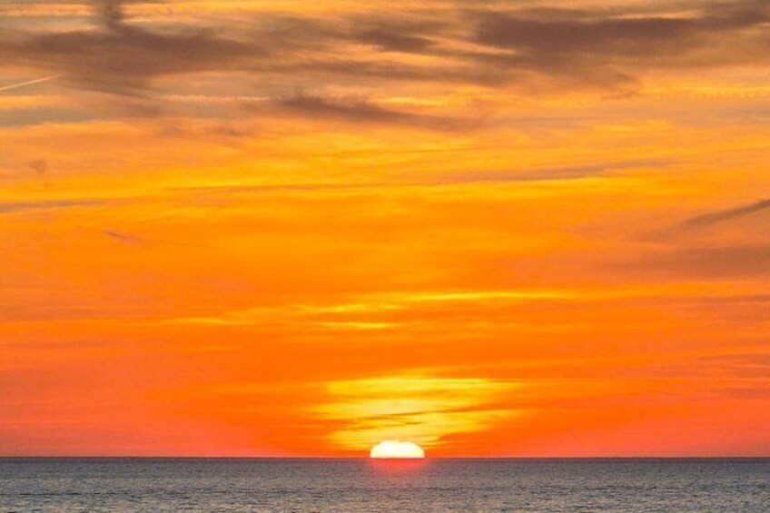 A sunset over the ocean with a visible sun near the horizon. 2