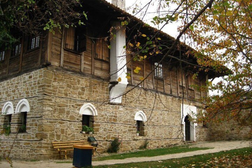 A stone building with wooden shutters, a bench, and a pathway. 5