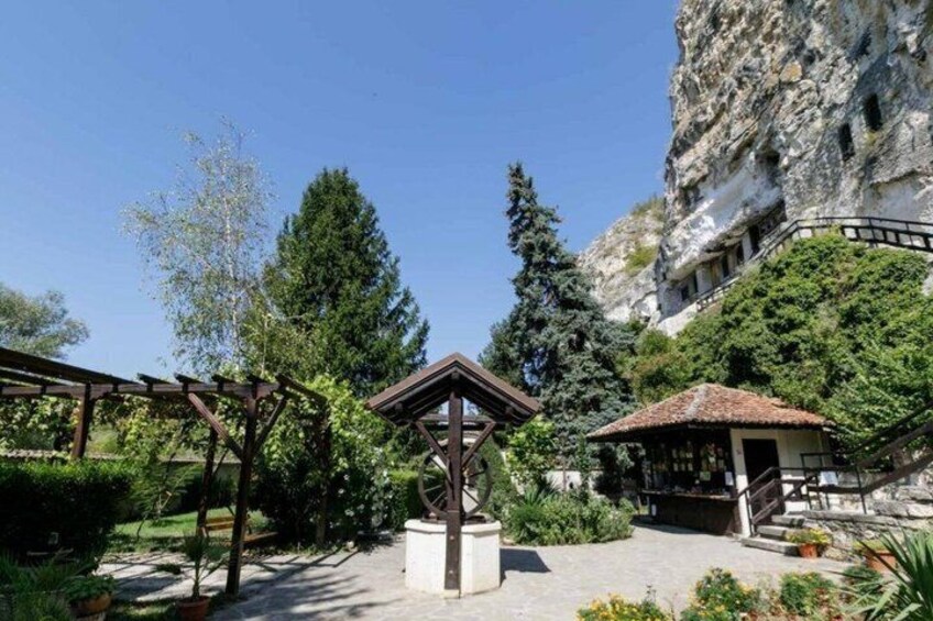 A garden with a gazebo, a wooden pergola, and a stone structure. 4