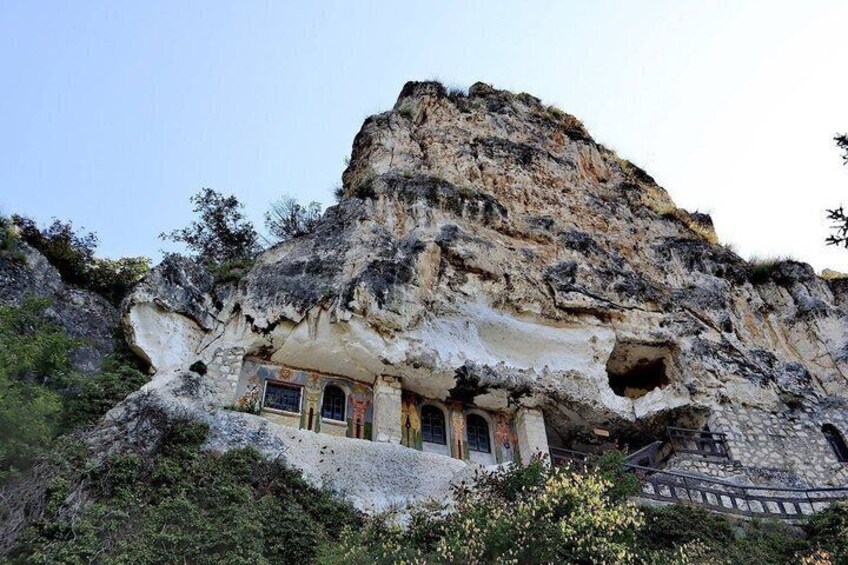 A cave dwelling with a staircase carved into the rock, surrounded by greenery. 3