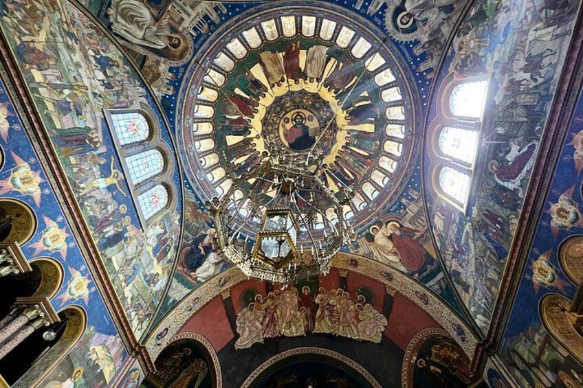 A detailed ceiling with a central circular design, surrounded by intricate frescoes and a chandelier. 3