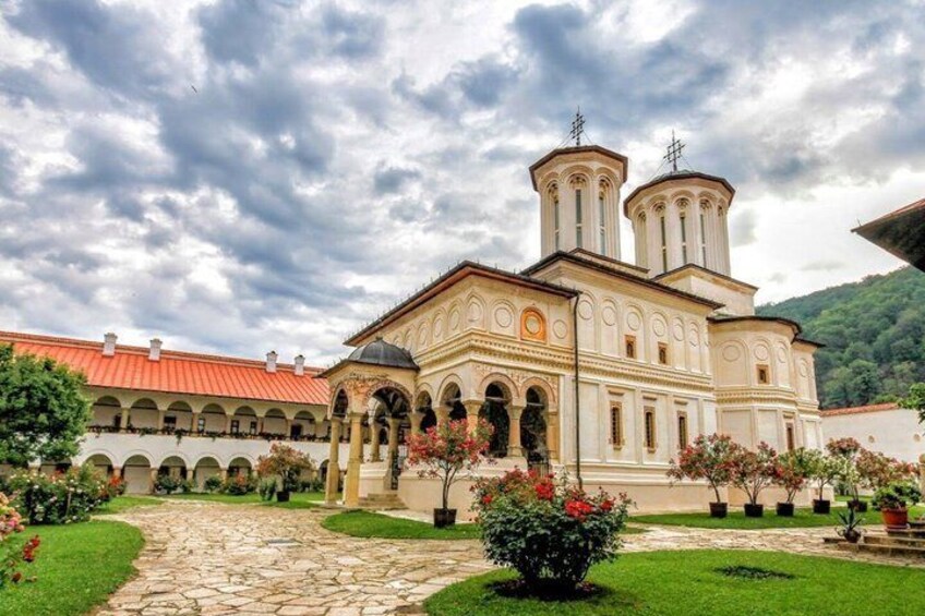 A historic building with a red roof, a central dome, and two bell towers. 1