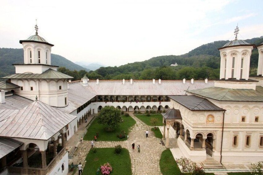 A monastery complex with multiple buildings, a central courtyard, and surrounding greenery. 4