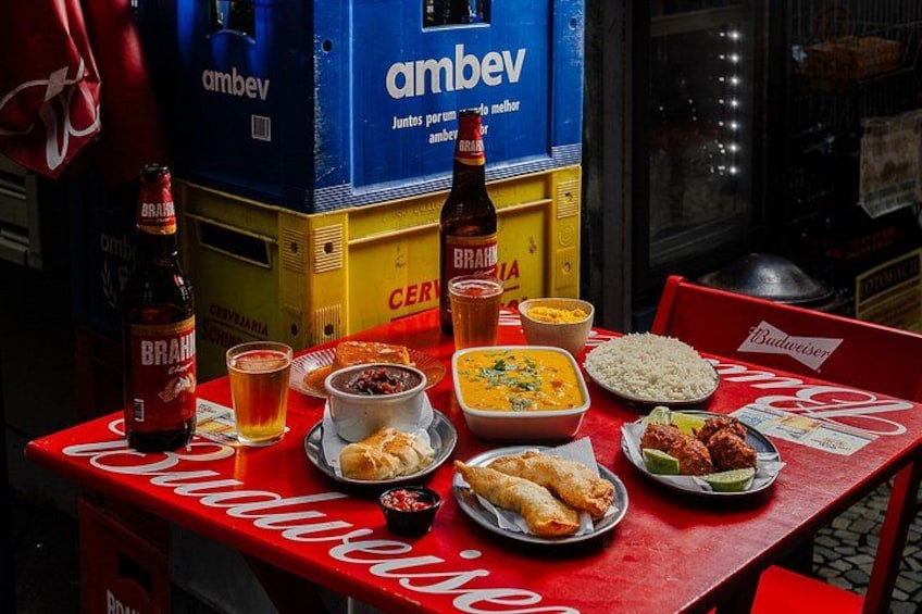 A table with various dishes, drinks, and a Budweiser box. 1
