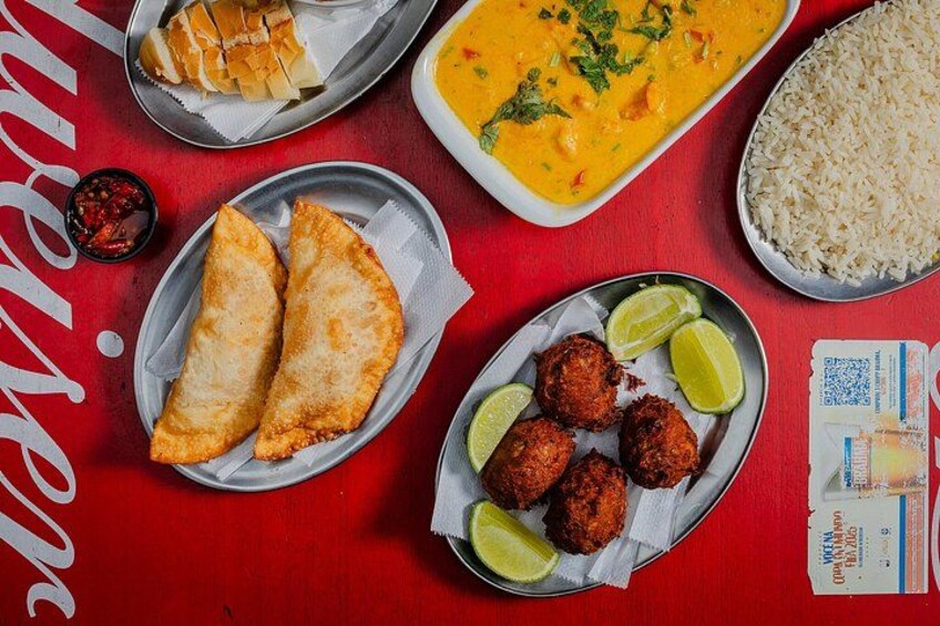 A variety of Indian dishes including samosas, meatballs, and a curry, served on a red table with a QR code and a menu. 4