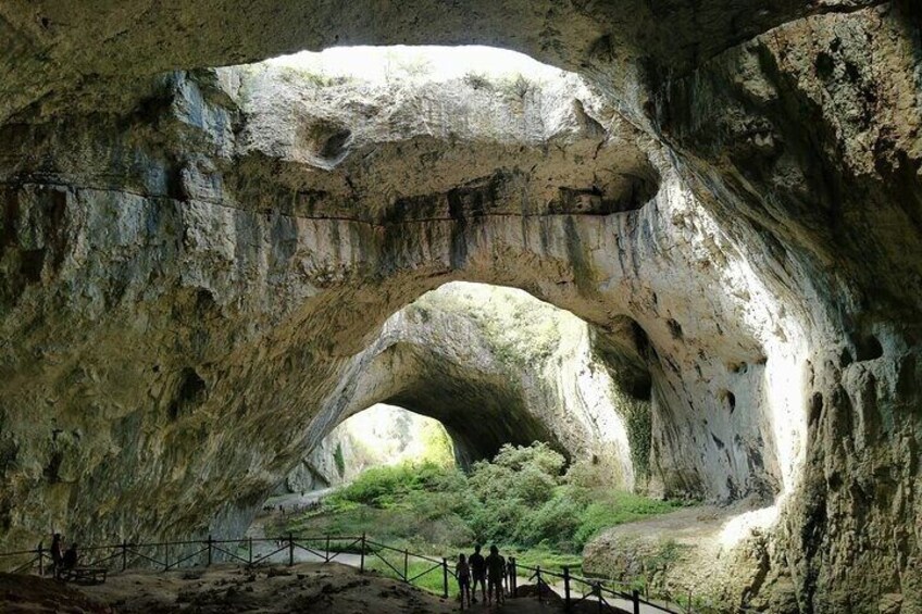 A large rock arch formation with a pathway leading through it. 1