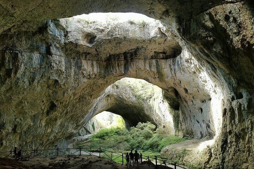 A large rock arch formation with a pathway leading through it. 1