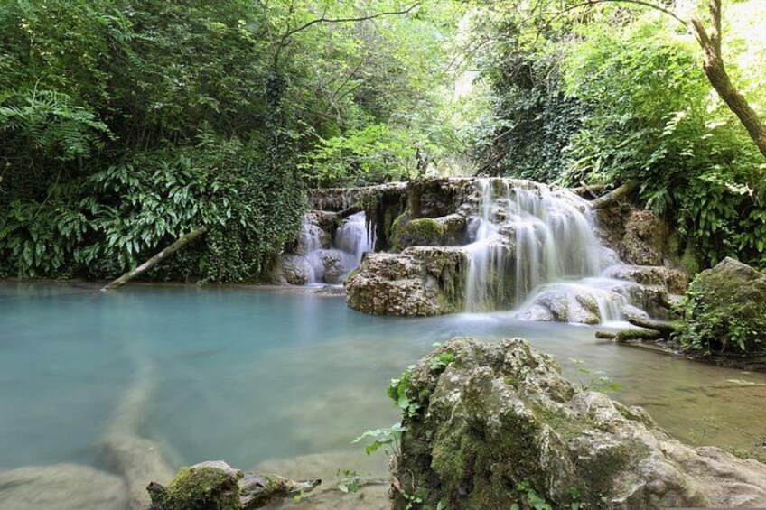 A waterfall in a forested area with clear water and rocks. 4