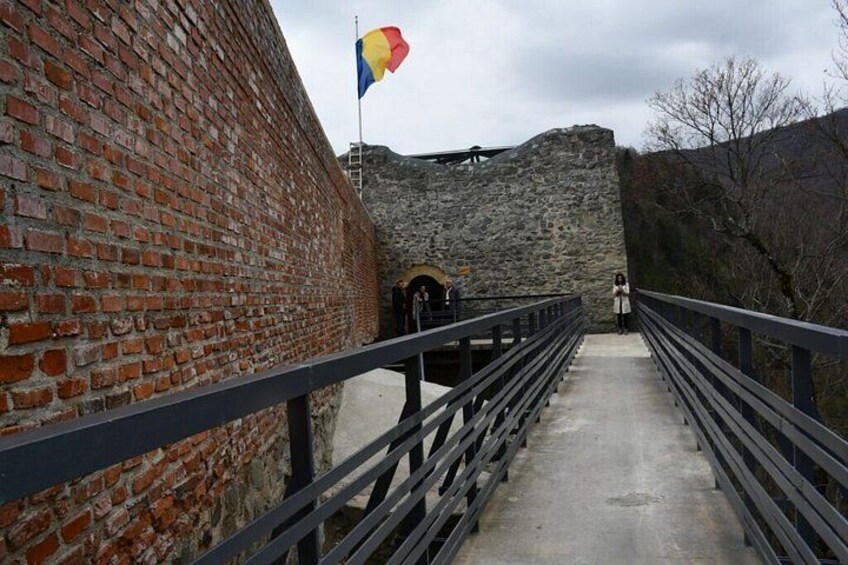 A brick wall, a stone wall, a metal railing, and a flag. 3