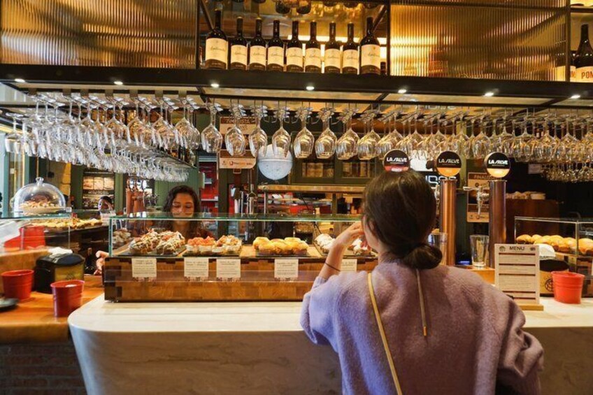 A bakery counter with pastries and wine bottles. 5