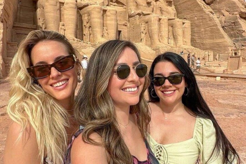 Three people in front of ancient rock-carved structures. 1