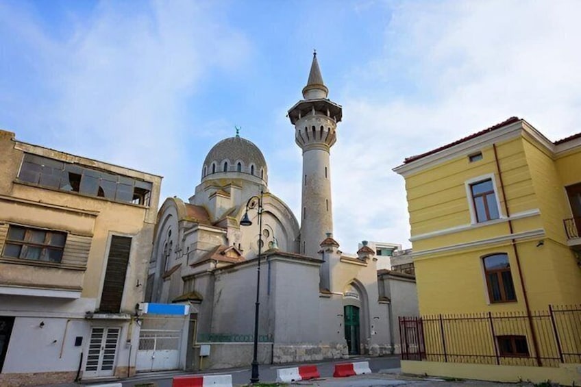 A mosque with a minaret and dome, surrounded by urban buildings. 3