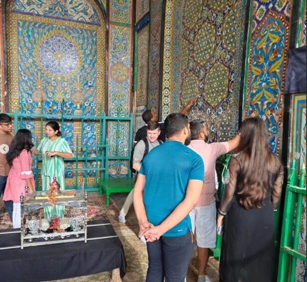 A group of people inside a building with ornate, colorful wall decorations and a table with religious items. 1