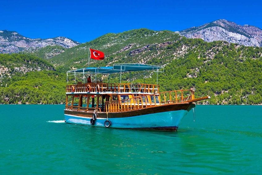 A boat with a Turkish flag on a turquoise sea with mountains in the background. 3