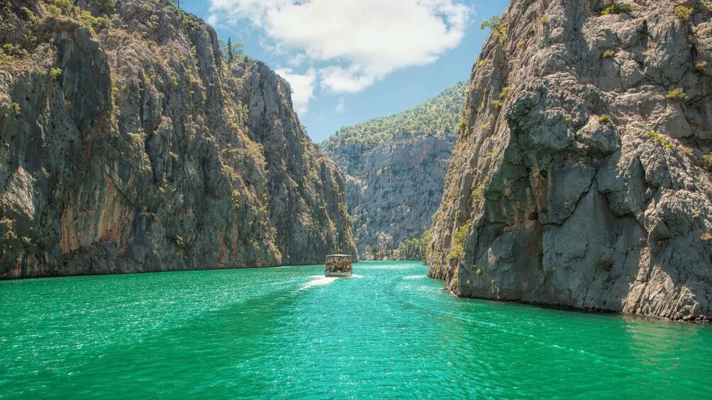 A boat on a turquoise river surrounded by rocky cliffs. 1