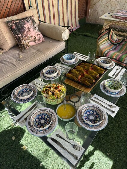 A glass-top dining table with a meal setup including a salad bowl, plates, a bowl of soup, and stuffed peppers. 2