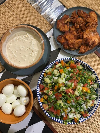 A meal with a bowl of soup, a plate of fried chicken, a salad, and a bowl of boiled eggs. 5