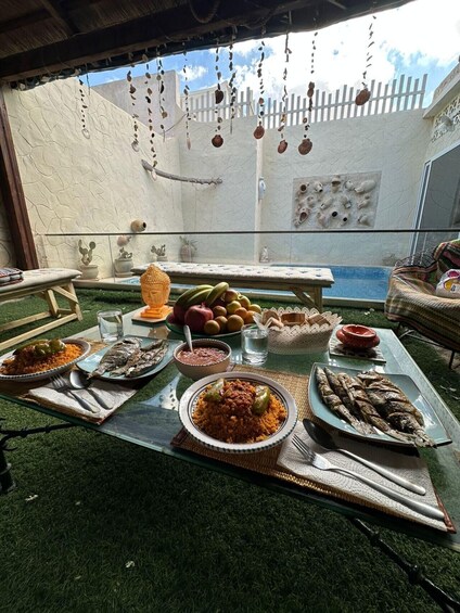A dining table set outdoors with various dishes, a Buddha statue, and hanging decorations. 1