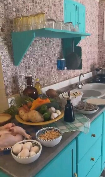 A kitchen with teal cabinets, a patterned backsplash, and various food items on the counter. 5