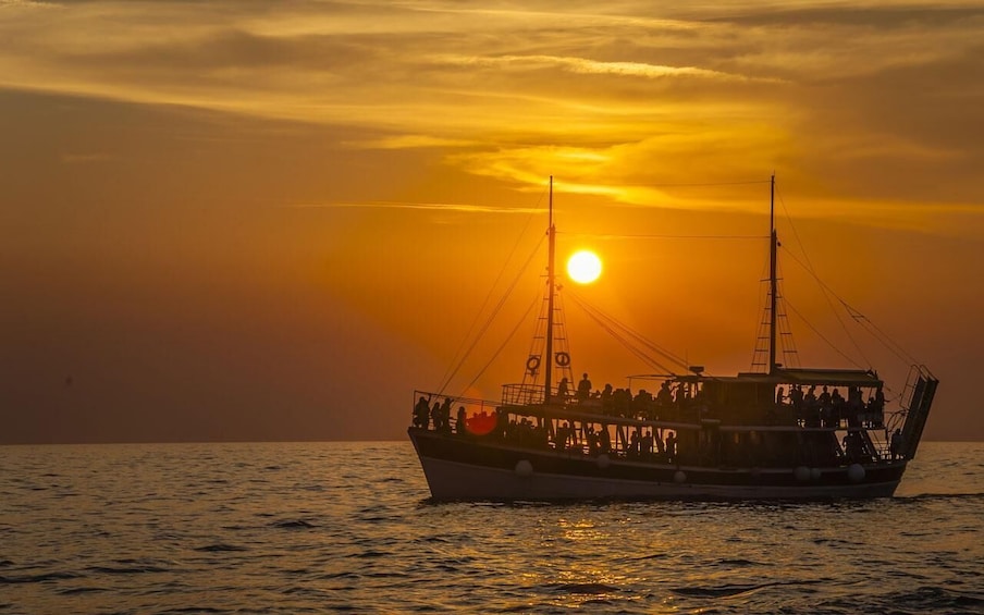 A boat with people on board during sunset. 2