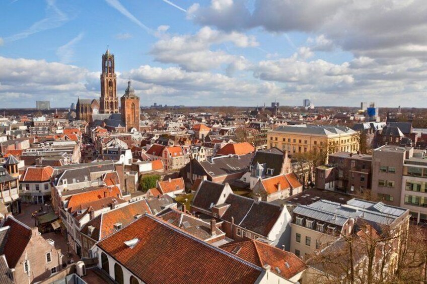 A cityscape with historic buildings, a prominent church tower, and a modern skyscraper in the distance. 4